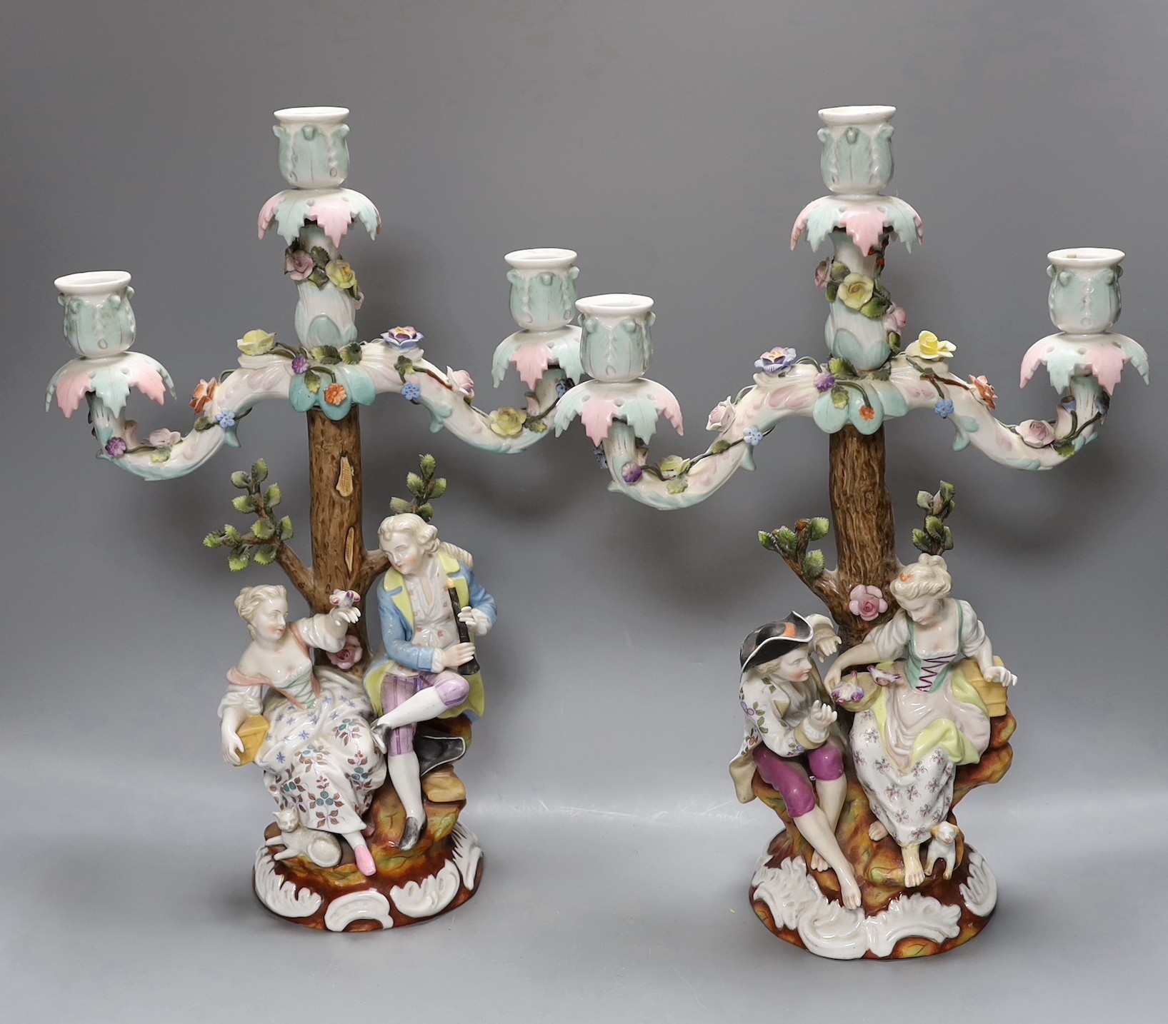 A pair of continental porcelain figural candlesticks and a similar candelabra base, together with a encrusted porcelain two handled jar with floral decoration, tallest 39cm, (4)